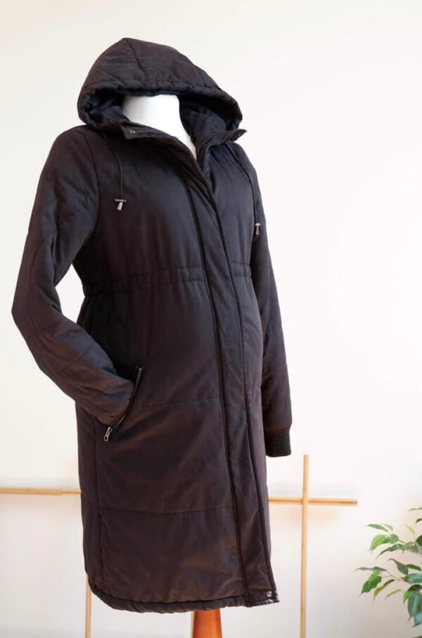 Full length image of a black maternity coat on a mannequin against a white wall.