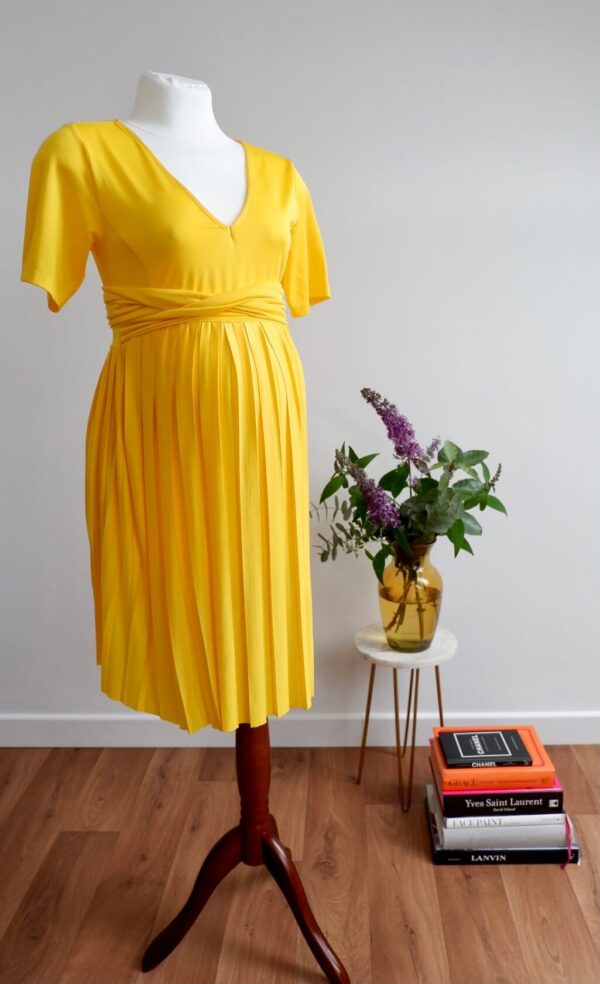 Image of yellow maternity dress with short sleeves and pleated skirt