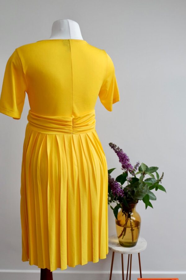 Image of the back of yellow maternity dress with short sleeves and pleated skirt