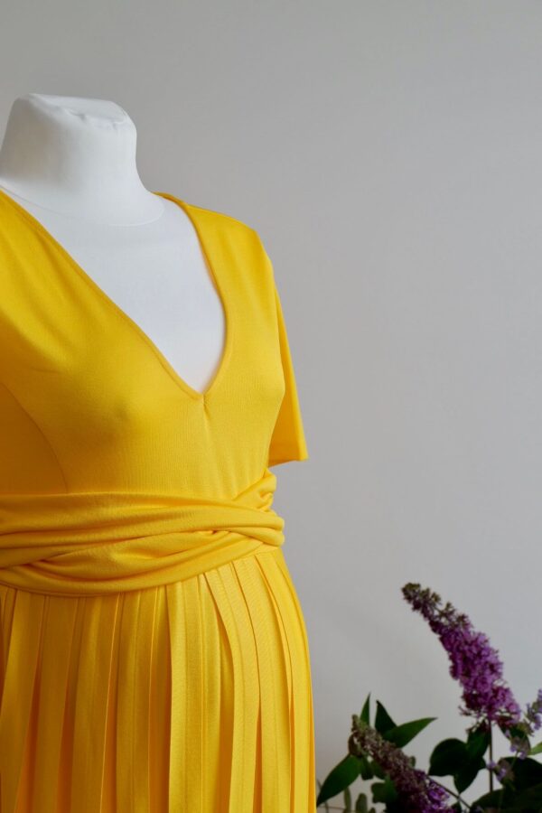 Image of yellow maternity dress with short sleeves and pleated skirt