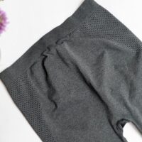 Flat lay image of grey leggings with a small black polka dot motif on the leg with a purple flower in the left corner