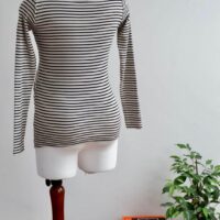 Back image of H&M maternity black and cream striped long sleeve top on a mannequin against a while wall background