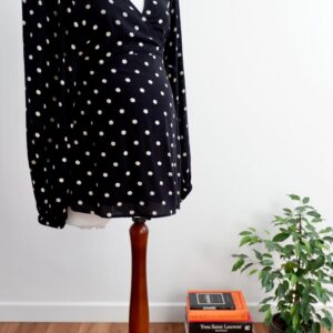 Image of H&M maternity black and cream polka dot maternity wrap top on a mannequin against a white wall.