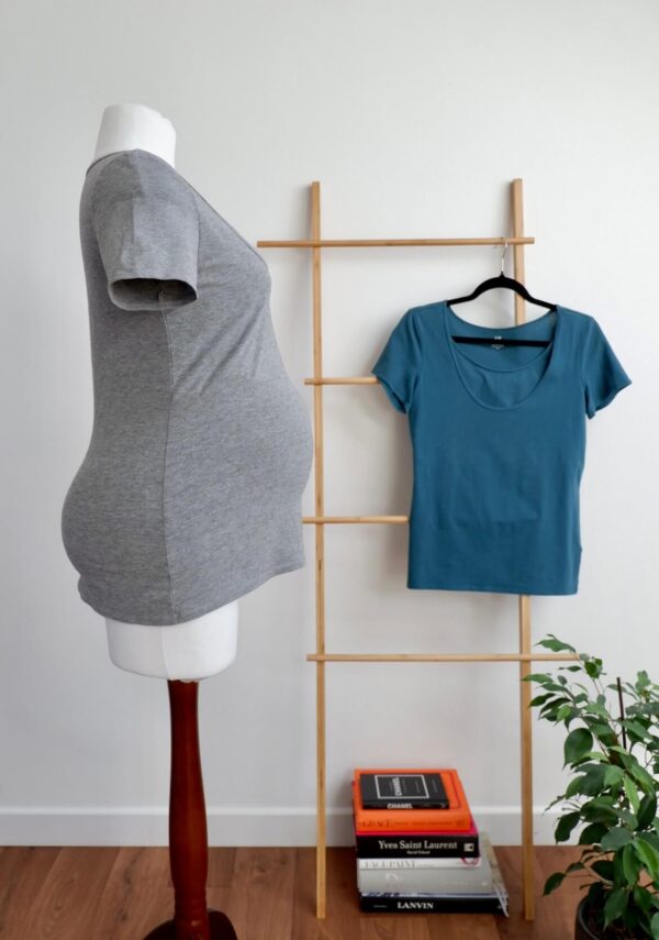 Side image of H&M grey nursing t-shirt on a mannequin with a H&M teal nursing t-shirt hanging on wall in the background