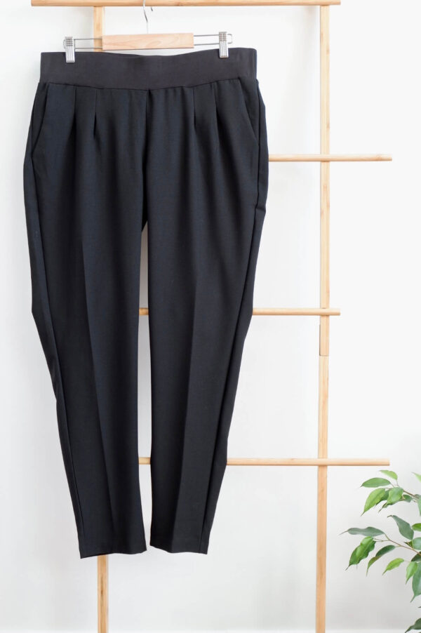 Image of Mamalicious black maternity cigarette trousers hanging on a small wooden ladder against a white wall.