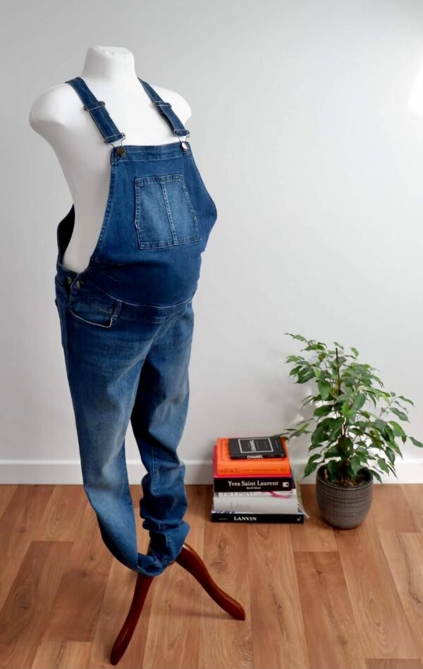 Image of Seraphine maternity dungarees on a mannequin against a while wall studio.