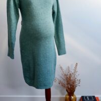 Sage green maternity knit dress on a mannequin agains a white wall