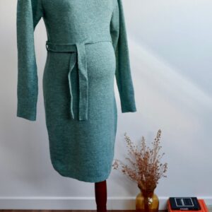 Sage green maternity knit dress on a mannequin agains a white wall