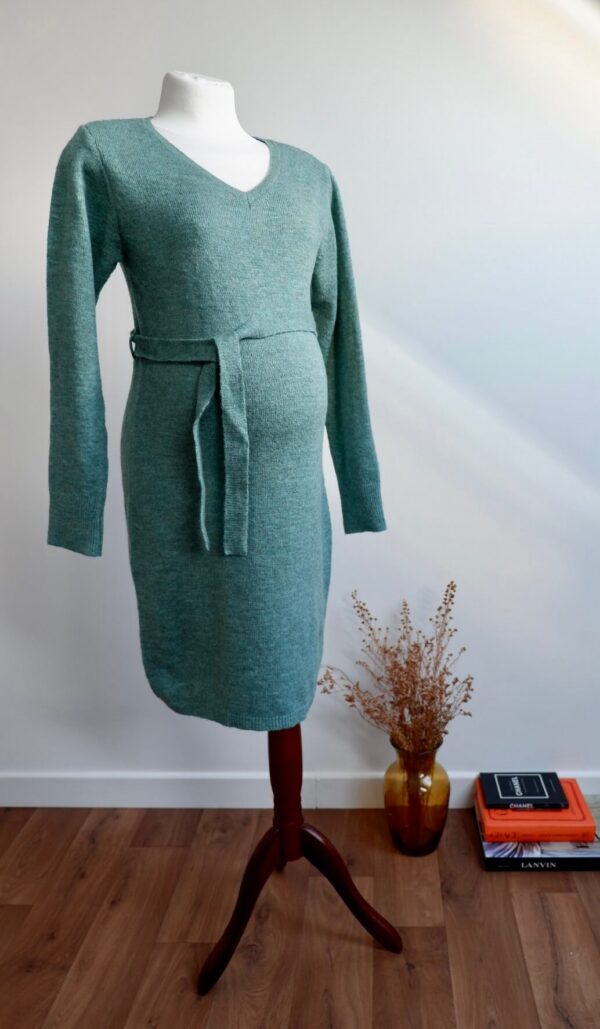 Sage green maternity knit dress on a mannequin agains a white wall