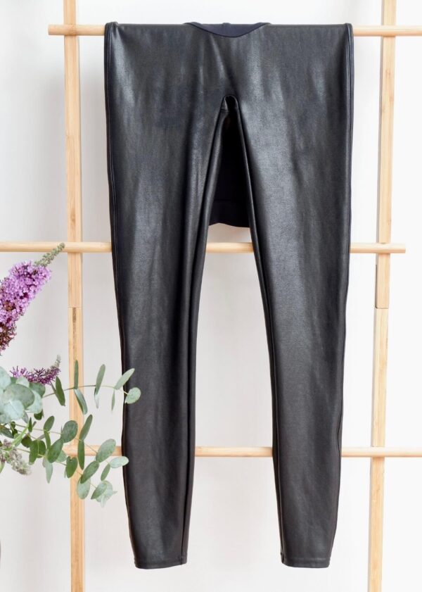 Image of maternity spanx faux leather leggings hanging on a ladder against a white wall