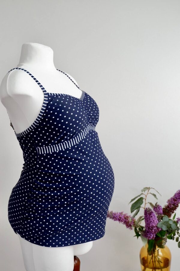 Side view of blue and white polka dot maternity swim vest on a mannequin