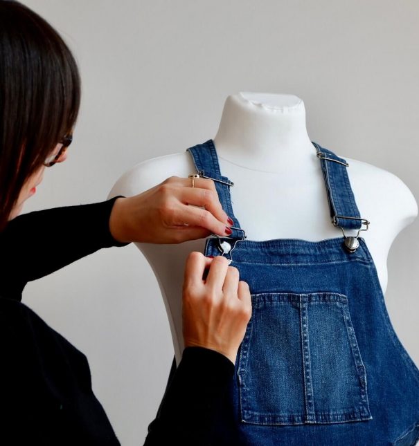 Imagine of Jo Leggiero, founder of Mother Dragon touching denim dungarees on a pregnant mannequin